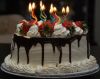 White_cream_birthday_cake_with_chocolate_sauce_and_strawberries_topping_and_cool_curved_candles_%28Custom%29.jpg